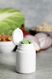 Photo of Bottle of pills near foodstuff on grey table. Prebiotic supplements