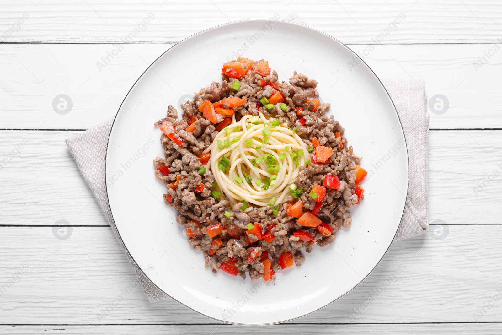 Photo of Tasty minced meat with spaghetti, vegetables and green onion on white wooden table, top view