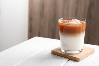 Photo of Glass of iced coffee on white wooden table. Space for text