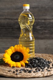 Photo of Sunflower cooking oil, seeds and yellow flower on wooden table