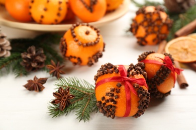 Pomander balls made of fresh tangerines with cloves  on white wooden table. Christmas atmosphere