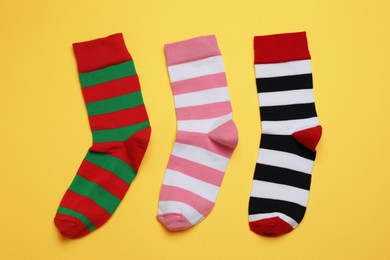Photo of Different striped socks on yellow background, flat lay