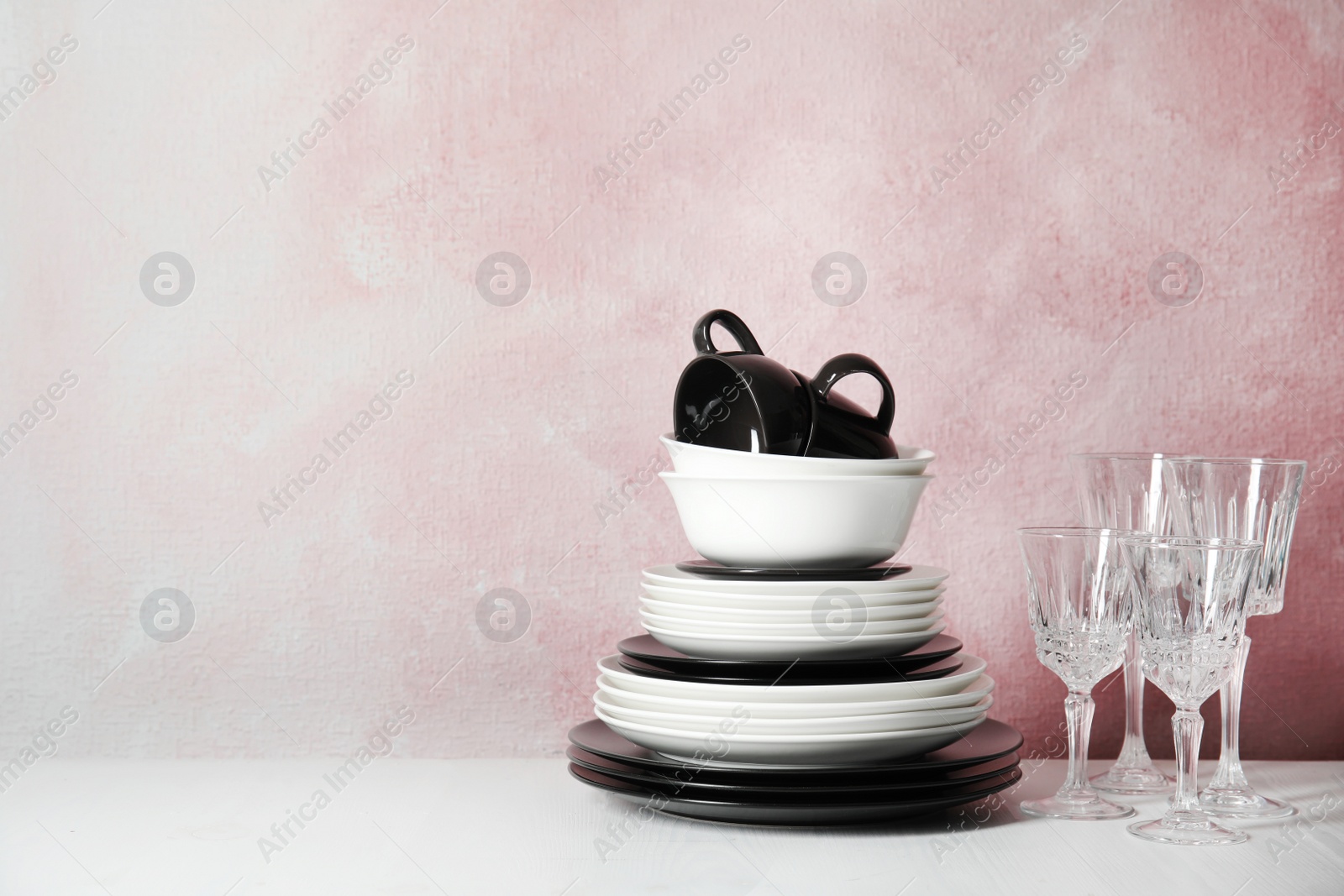 Photo of Set of dinnerware on table against color background with space for text. Interior element