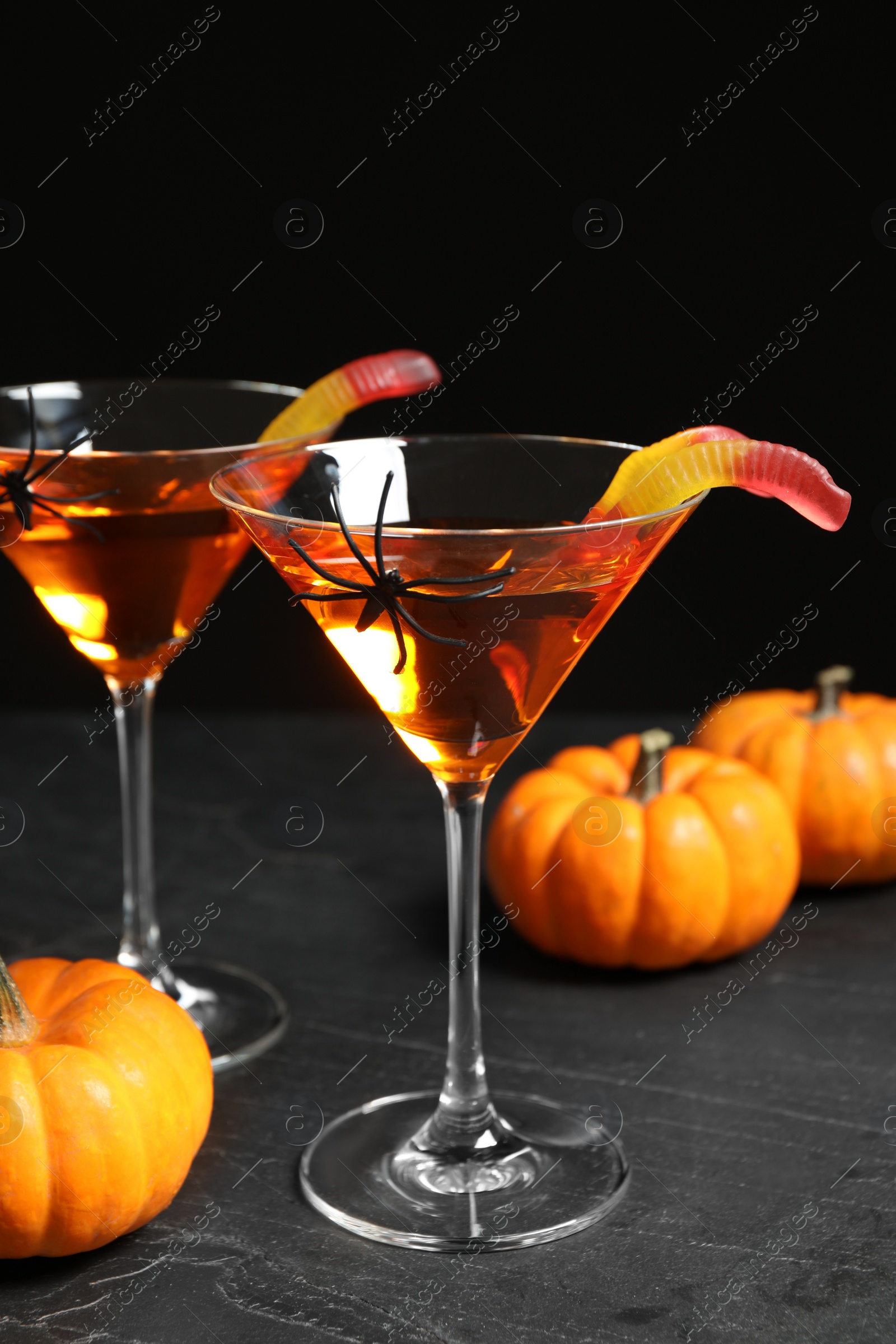 Photo of Decorated glasses with drinks on grey table. Halloween celebration