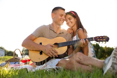 Photo of Happy couple with guitar on picnic in park