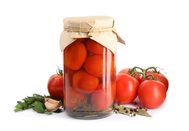 Pickled tomatoes in glass jar and products on white background