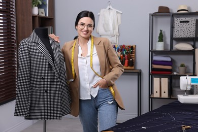 Photo of Dressmaker near mannequin with jacket in workshop