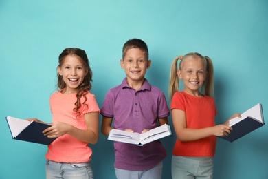 Portrait of little children reading books on turquoise background