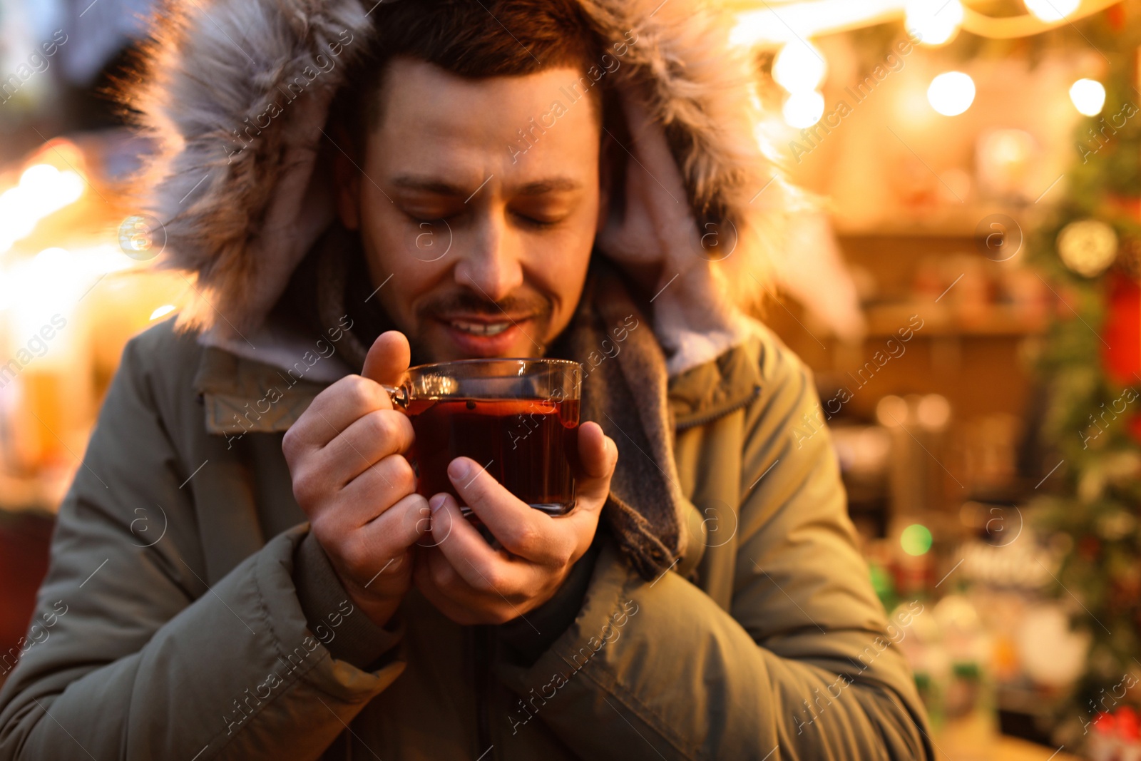 Photo of Happy man with mulled wine at winter fair