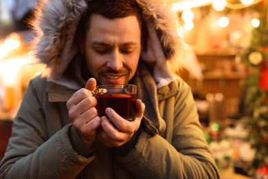 Happy man with mulled wine at winter fair