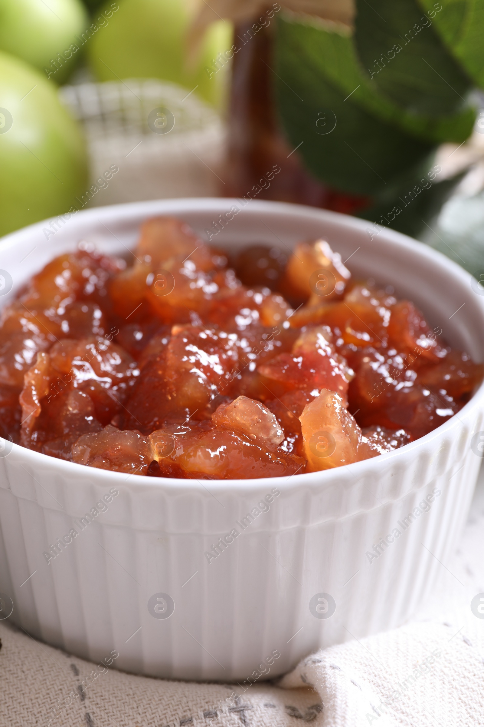 Photo of Bowl of delicious apple jam on white tablecloth, closeup