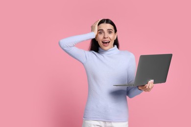 Photo of Shocked woman with laptop on pink background, space for text