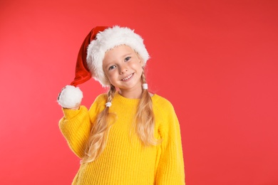 Photo of Happy little child in Santa hat on red background. Christmas celebration