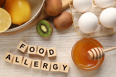 Food allergy. Different fresh products and cubes on light wooden table, flat lay