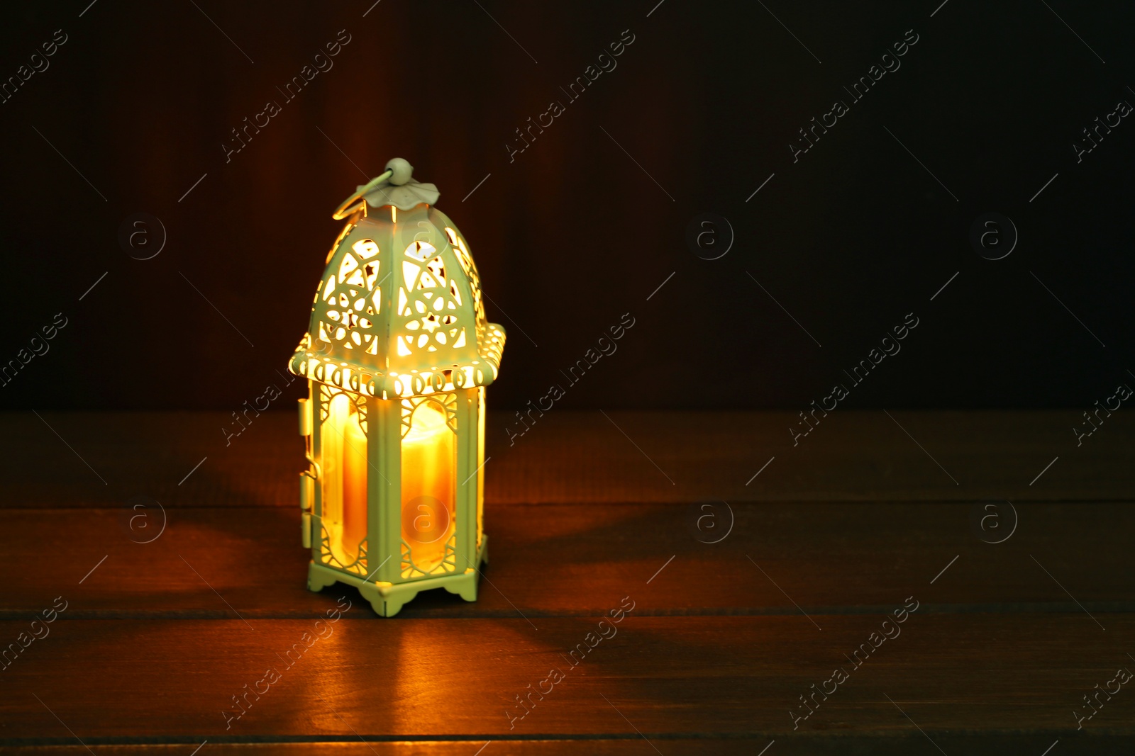 Photo of Decorative Arabic lantern on table against dark background. Space for text