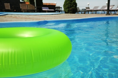 Photo of Bright inflatable ring floating in swimming pool on sunny day, outdoors. Space for text