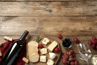 Flat lay composition with red wine and snacks on wooden table, space for text