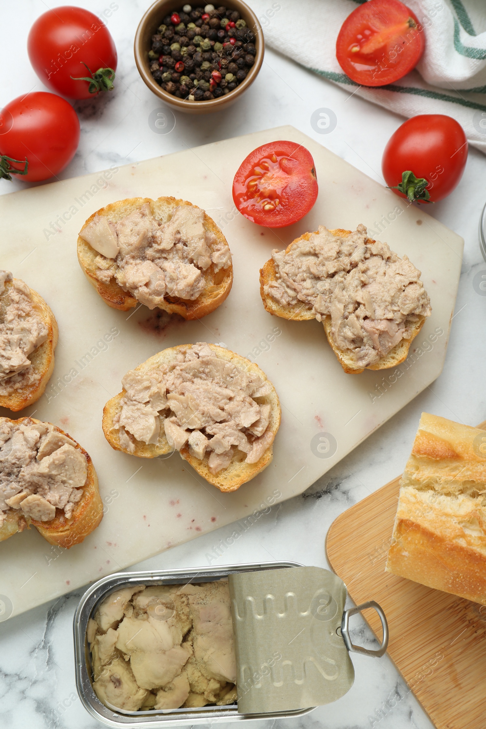 Photo of Tasty sandwiches with cod liver on white marble table, flat lay