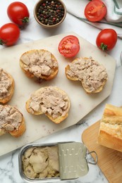 Photo of Tasty sandwiches with cod liver on white marble table, flat lay