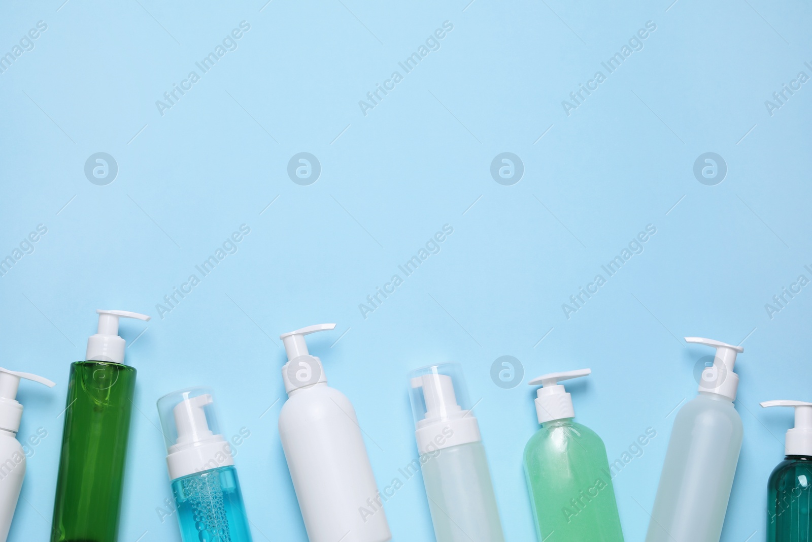 Photo of Different cleansers on light blue background, flat lay with space for text. Cosmetic product