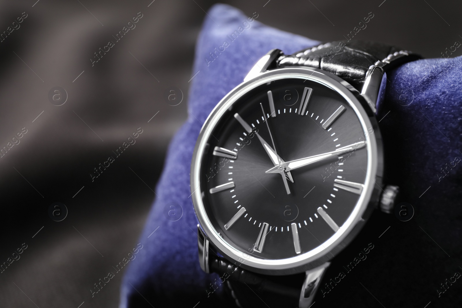 Photo of Small decorative pillow with luxury wrist watch on black background, closeup. Fashion accessory