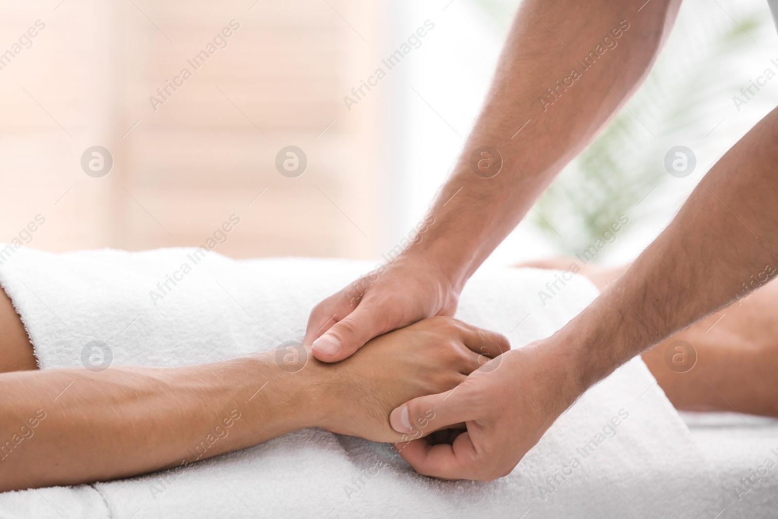 Photo of Young man receiving massage in salon, closeup