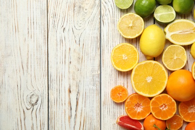 Different citrus fruits on wooden background, top view. Space for text