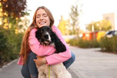 Photo of Young woman hugging her English Springer Spaniel dog outdoors. Space for text