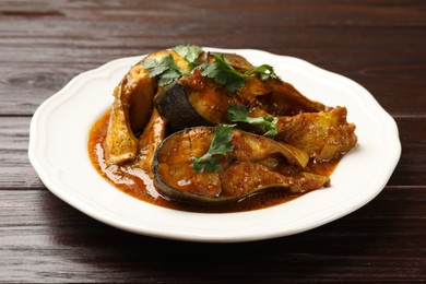 Photo of Tasty fish curry on wooden table, closeup. Indian cuisine