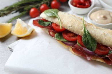 Photo of Delicious sandwich with bresaola, tomato, onion and cheese on table, closeup. Space for text