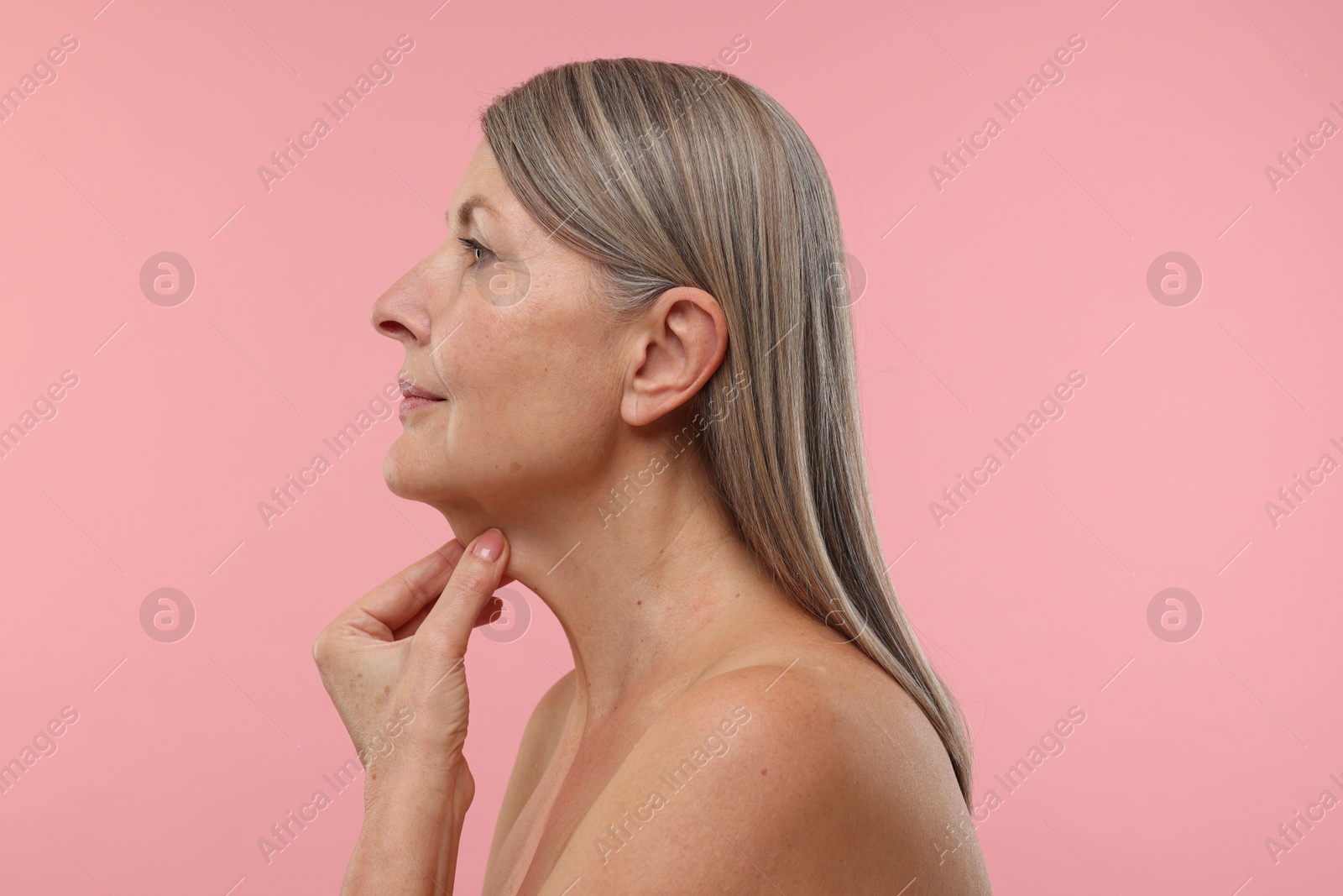 Photo of Beautiful woman touching her neck on pink background