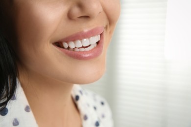 Photo of Young woman with healthy teeth on blurred background, closeup. Space for text