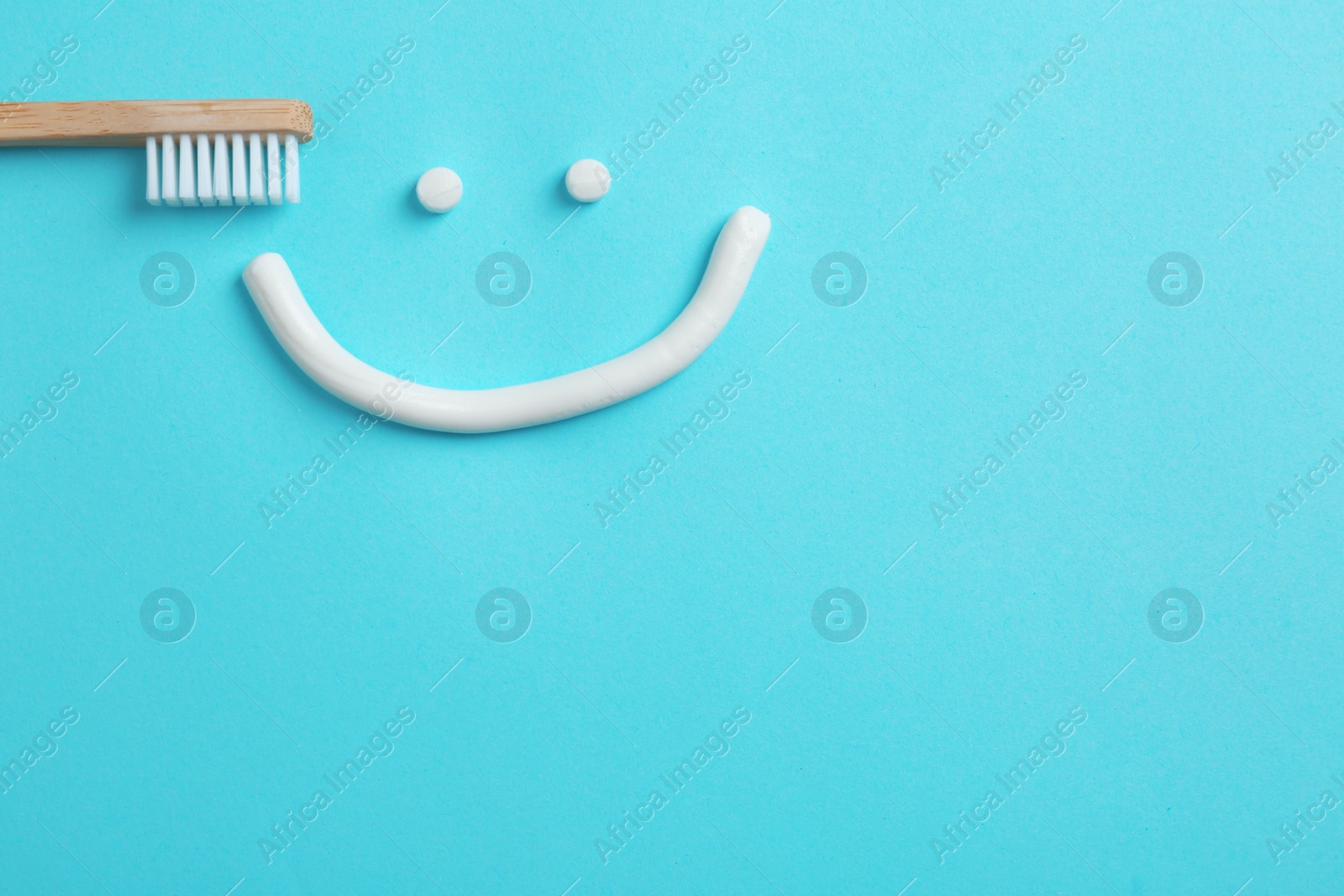 Photo of Smiling face made of toothpaste, brush and space for text on color background, top view