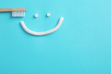 Photo of Smiling face made of toothpaste, brush and space for text on color background, top view