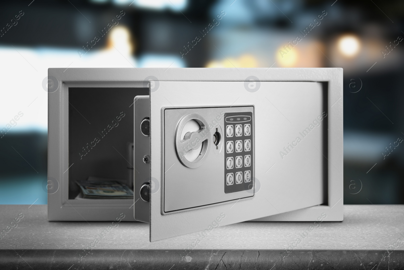 Image of Open steel safe with electronic lock and money on grey table indoors