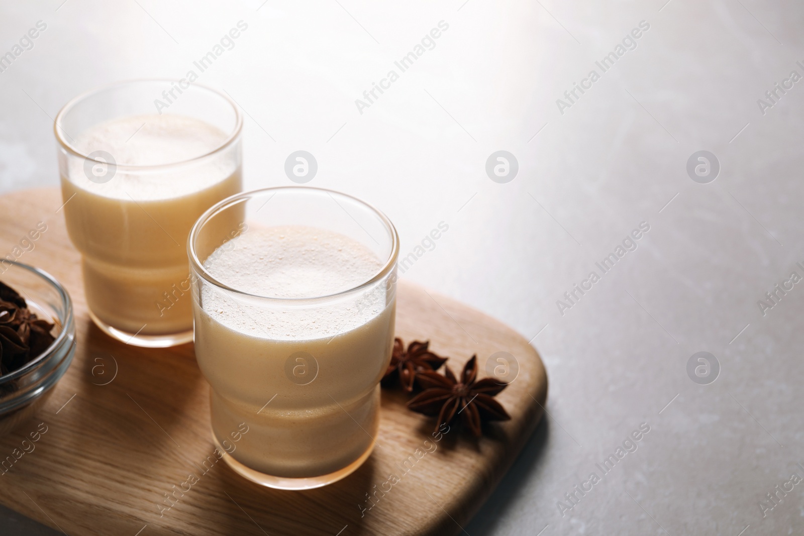 Photo of Glasses of delicious eggnog with anise on grey marble table, space for text
