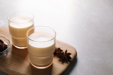 Glasses of delicious eggnog with anise on grey marble table, space for text