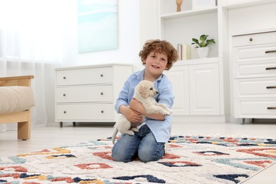 Photo of Little boy with cute puppy on carpet at home