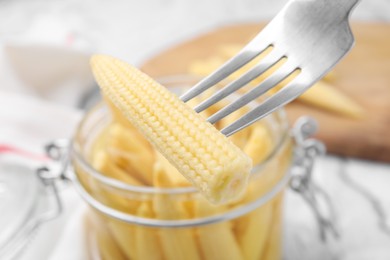 Photo of Pickled baby corn on fork at table, closeup