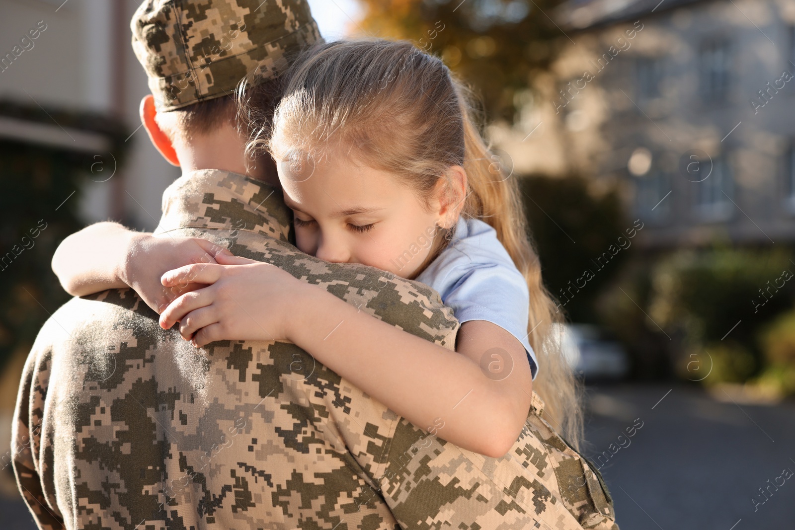 Photo of Daughter hugging her father in Ukrainian military uniform outdoors. Family reunion