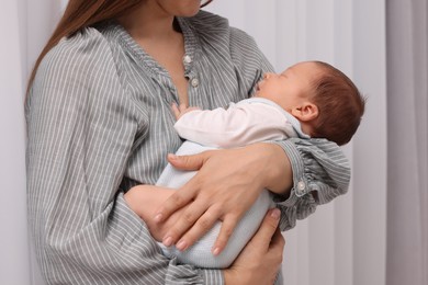 Mother holding her cute newborn baby indoors, closeup