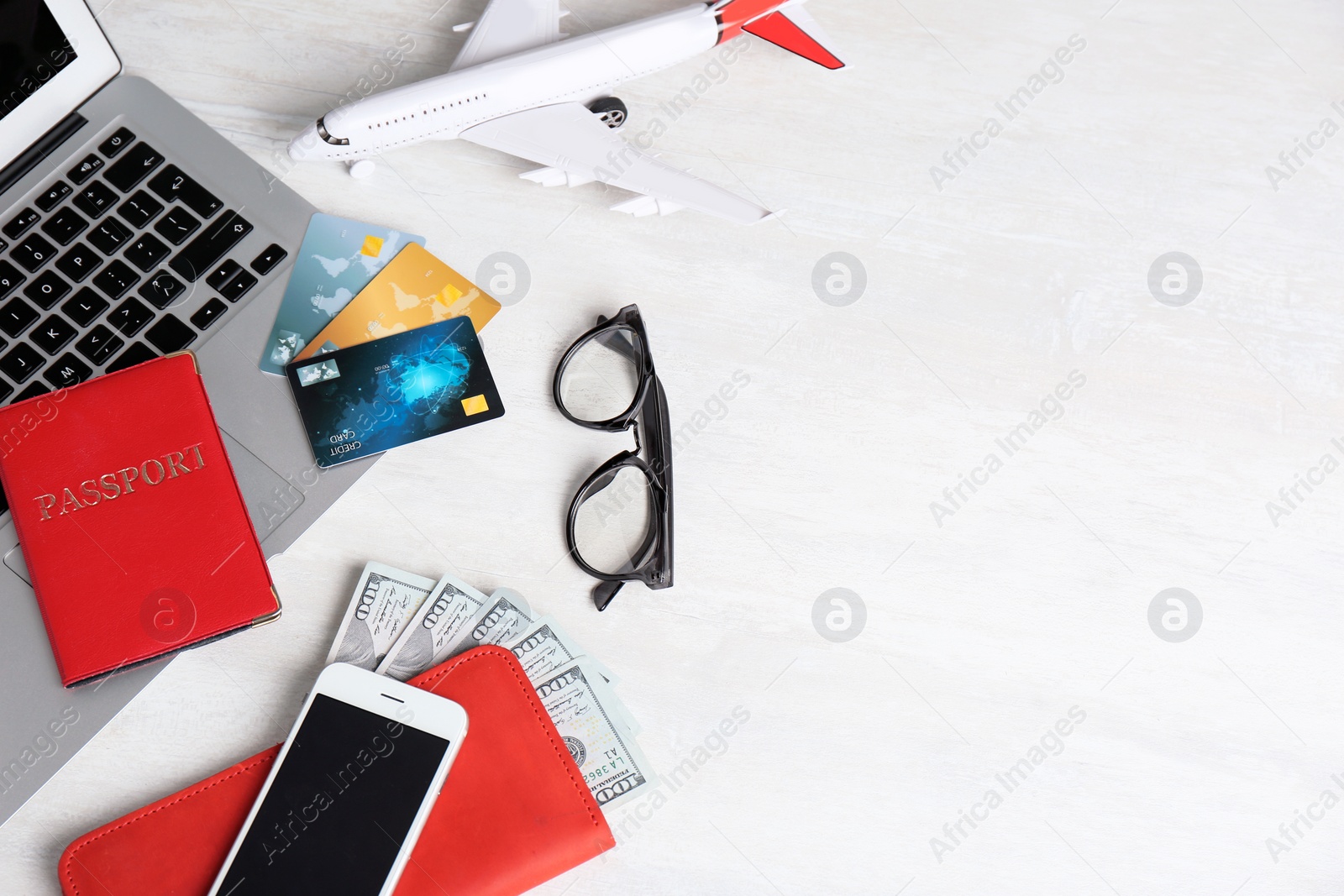 Photo of Smartphone, laptop, passport and money on light background, space for text. Travel agency