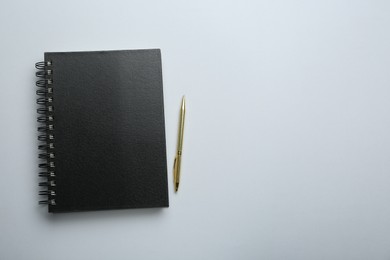 Photo of One notebook and pen on light grey background, top view. Space for text