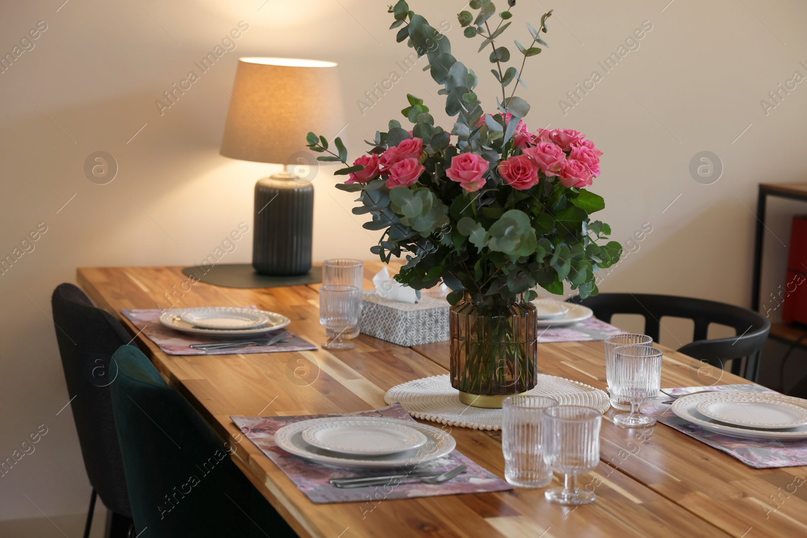 Photo of Beautiful table setting with bouquet indoors. Roses and eucalyptus branches in vase