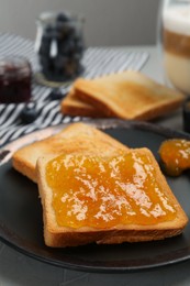 Photo of Toast with tasty orange jam served on grey table, closeup. Space for text