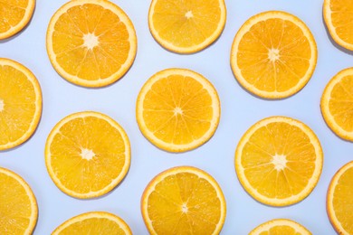 Slices of juicy orange on light blue background, flat lay