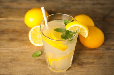 Photo of Cool freshly made lemonade in glass on wooden table