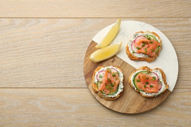 Photo of Tasty canapes with salmon served on wooden table, top view. Space for text