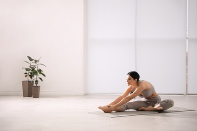 Photo of Young woman stretching leg in yoga studio. Janu Sirsasana pose variation