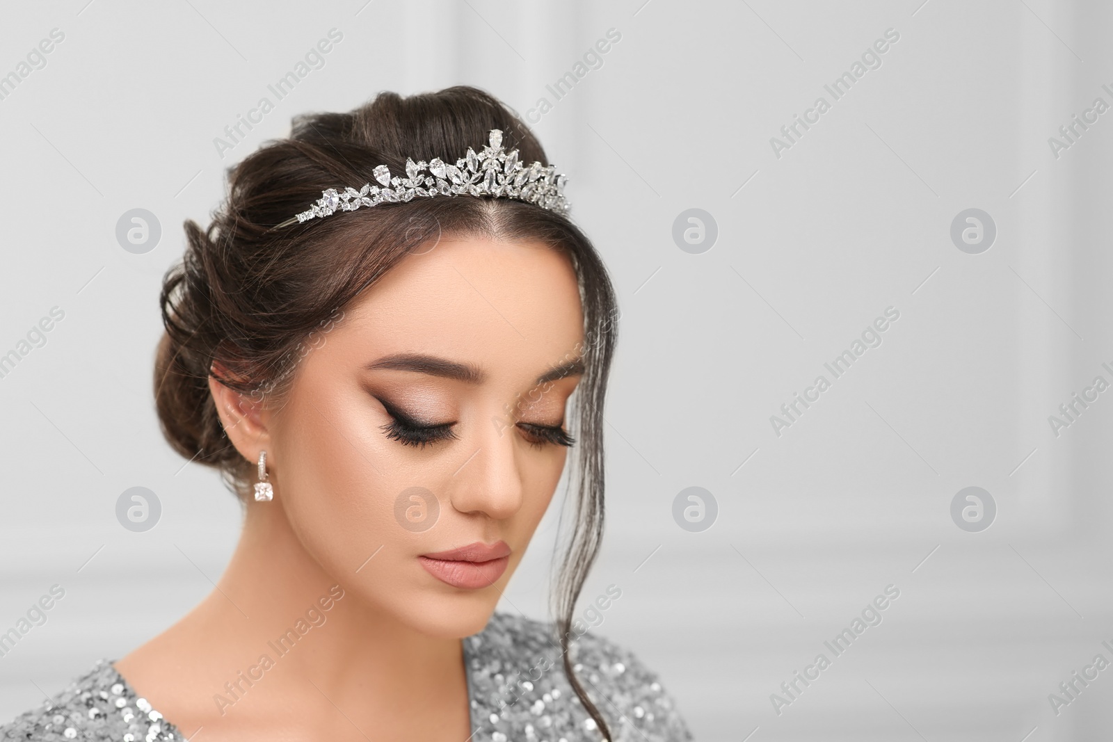 Photo of Beautiful young woman wearing luxurious tiara indoors, space for text